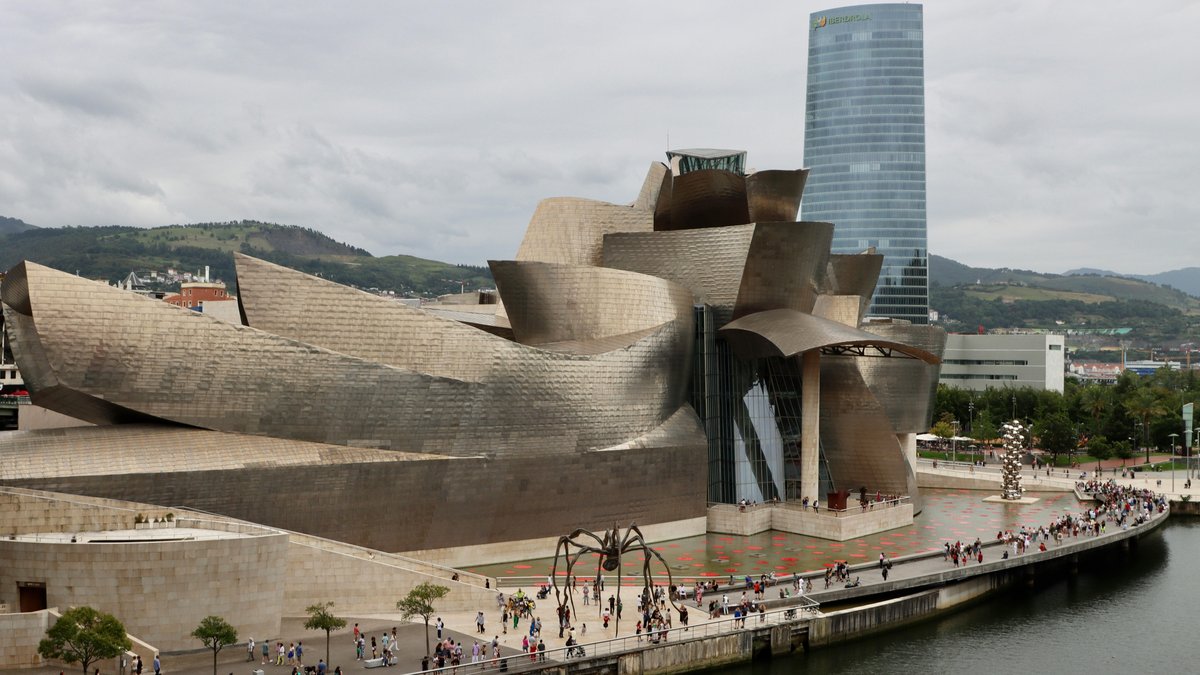 Vista del Museo Guggenheim di Bilbao con il rivestimento in titanio riflesso sul fiume Nervión